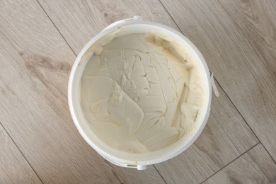 Photo of Bucket with plaster and putty knife on floor indoors, top view