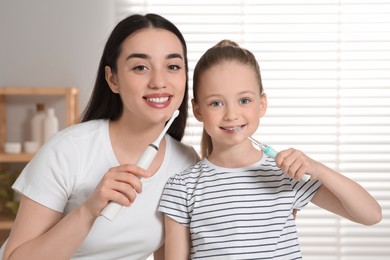 Mother and her daughter brushing teeth together in bathroom