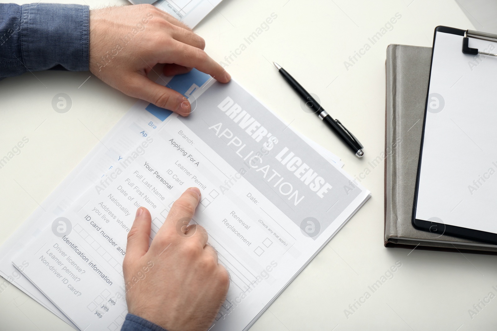 Photo of Man with driver's license application form at white table, above view