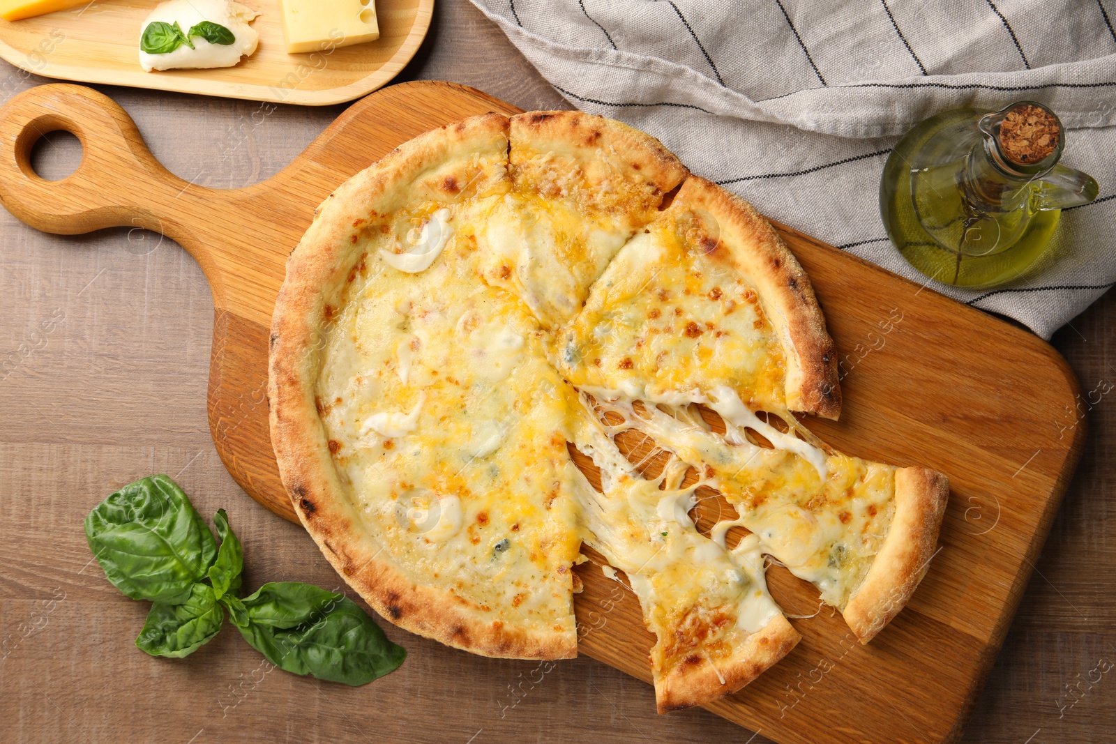 Photo of Delicious cut cheese pizza and ingredients on wooden table, flat lay