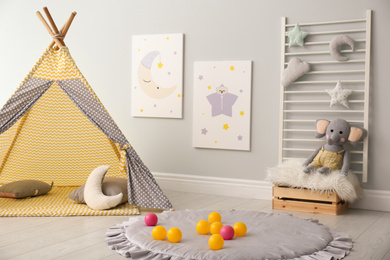 Photo of Stylish child's room interior with adorable paintings and play tent