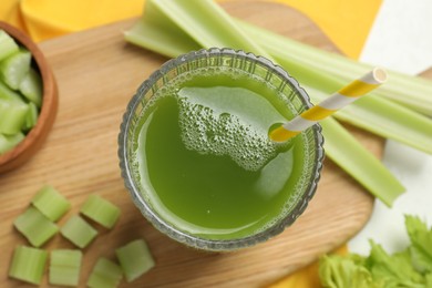 Glass of delicious celery juice and vegetables on wooden board, flat lay