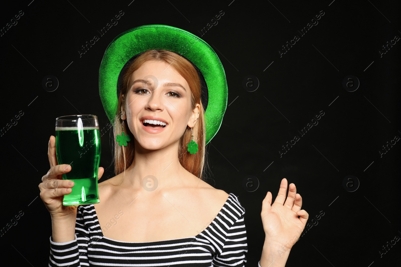 Photo of Young woman with green beer on black background. St. Patrick's Day celebration