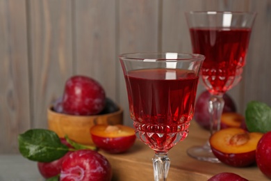 Photo of Delicious plum liquor on blurred background, closeup. Homemade strong alcoholic beverage