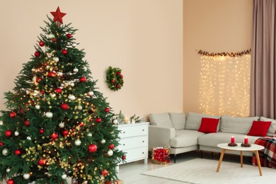 Beautiful tree decorated for Christmas in room with stylish furniture. Interior design