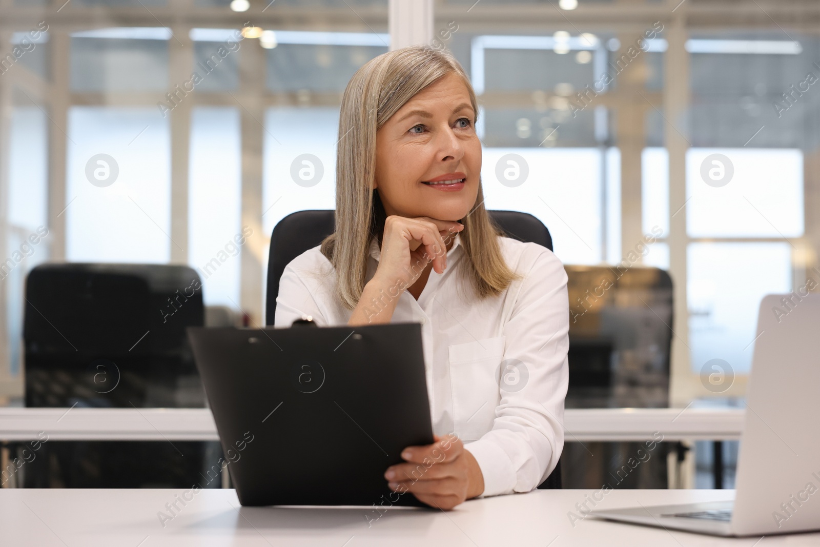 Photo of Smiling woman with clipboard working in office. Lawyer, businesswoman, accountant or manager