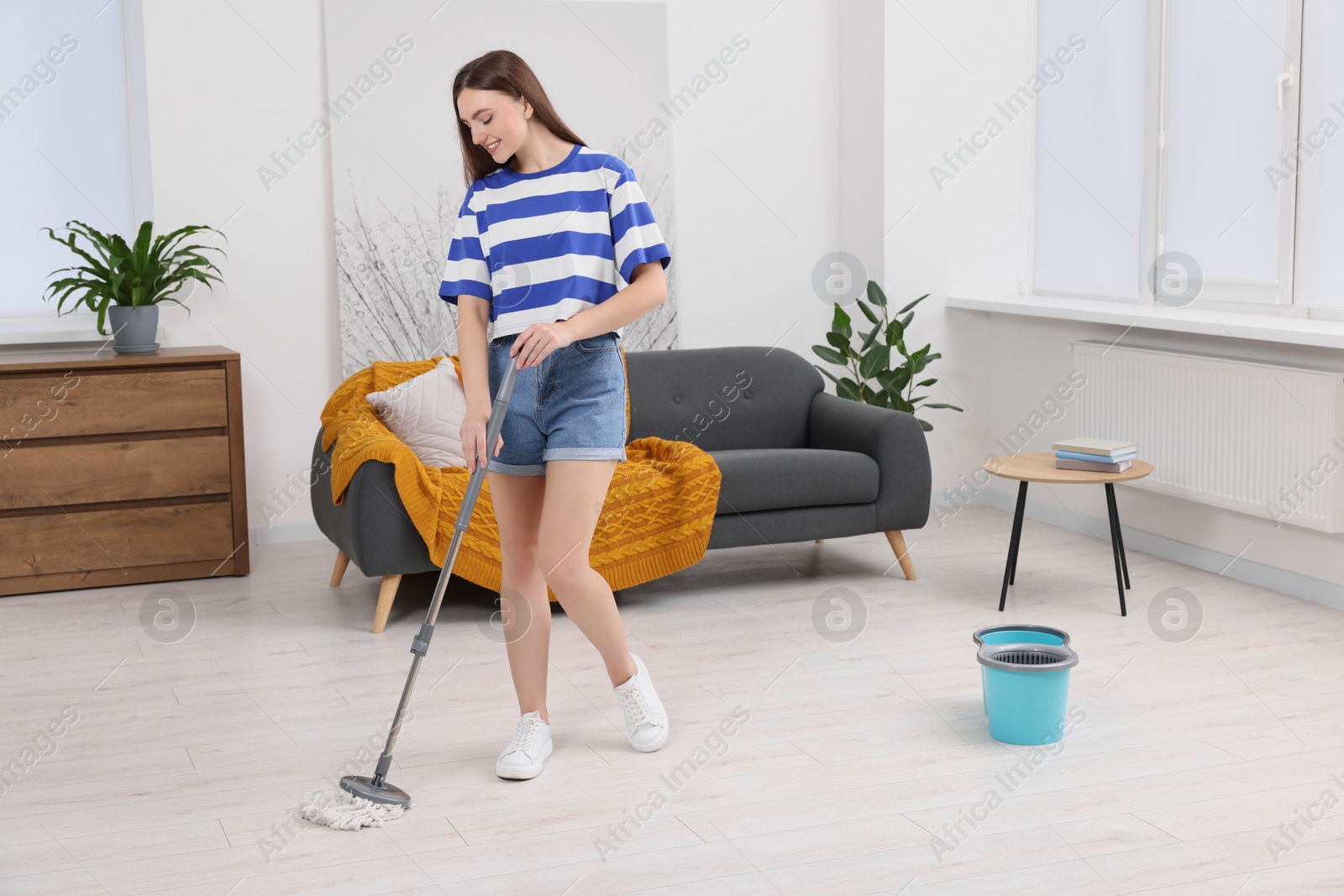 Photo of Happy woman cleaning floor with mop at home. Space for text