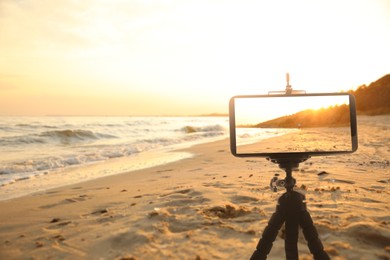 Image of Taking photo of beautiful sandy beach with smartphone mounted on tripod