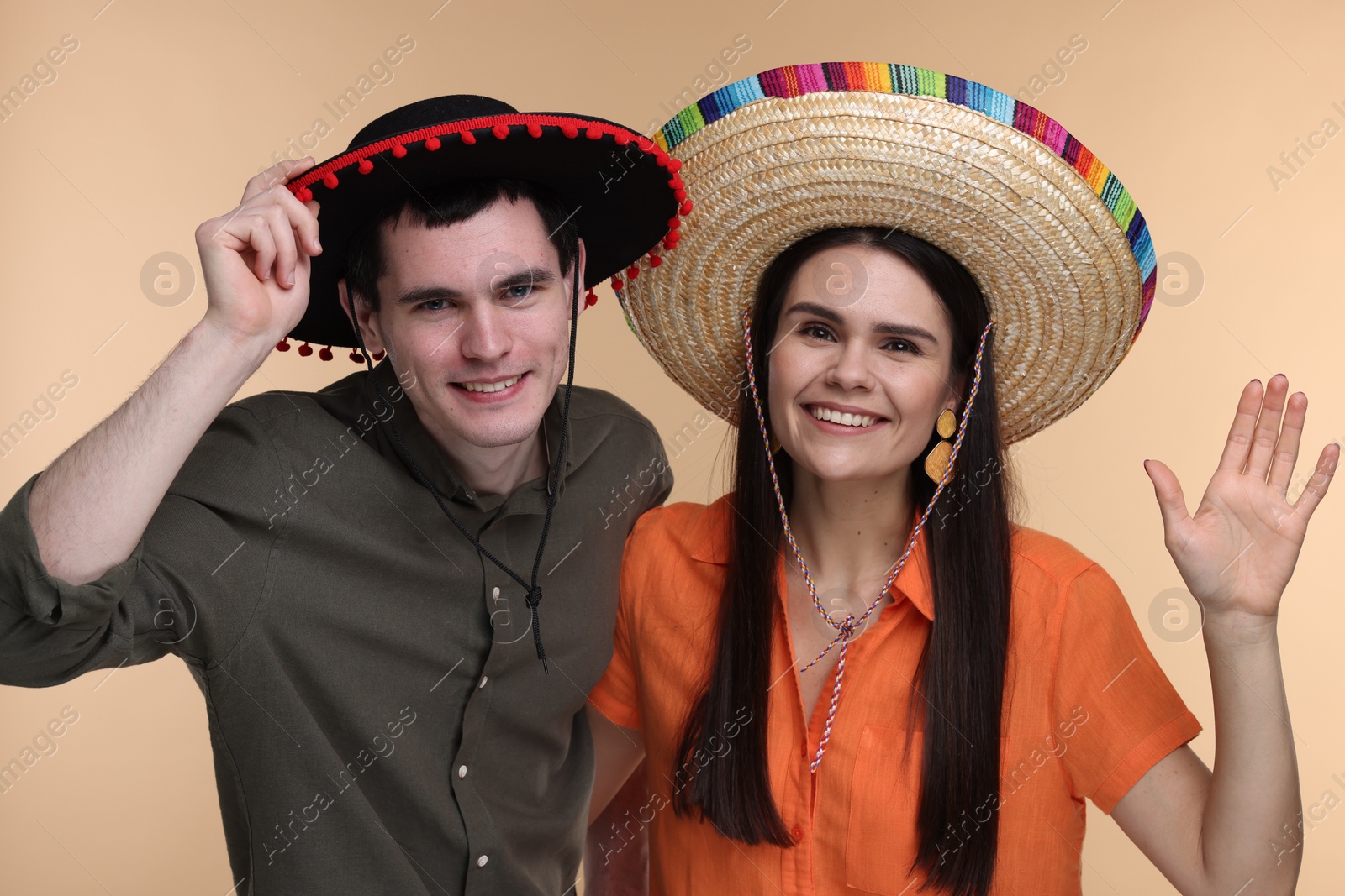 Photo of Lovely couple woman in Mexican sombrero hats on beige background