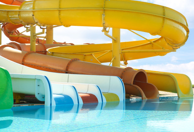 Photo of Different colorful slides and swimming pool in water park on sunny day