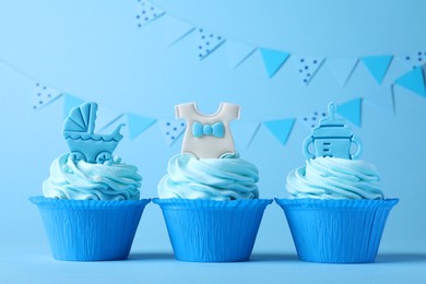 Beautifully decorated baby shower cupcakes for boy with cream and toppers on light blue background