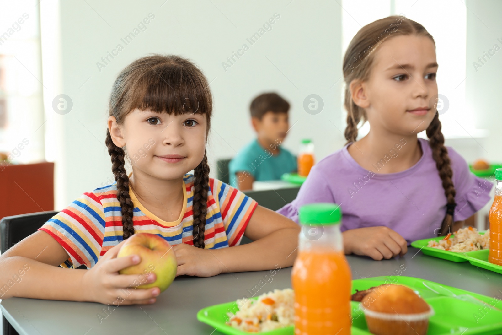 Photo of Children sitting at table and eating healthy food during break at school