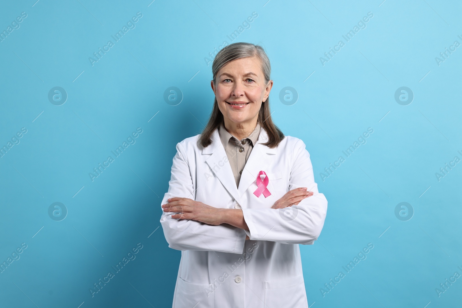 Photo of Mammologist with pink ribbon on light blue background. Breast cancer awareness