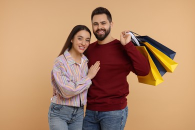 Photo of Happy couple with shopping bags on beige background