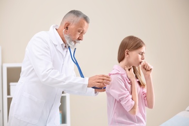 Photo of Doctor examining coughing teenage girl at clinic