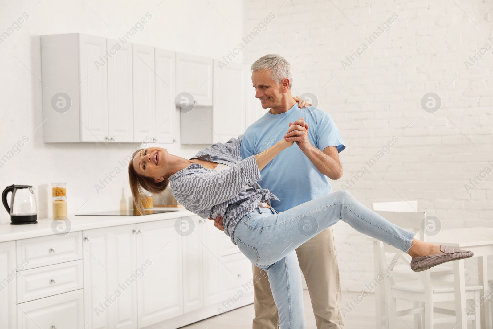 Photo of Happy senior couple dancing together in kitchen