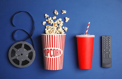 Photo of Flat lay composition with popcorn, cinema reel and TV remote on color background