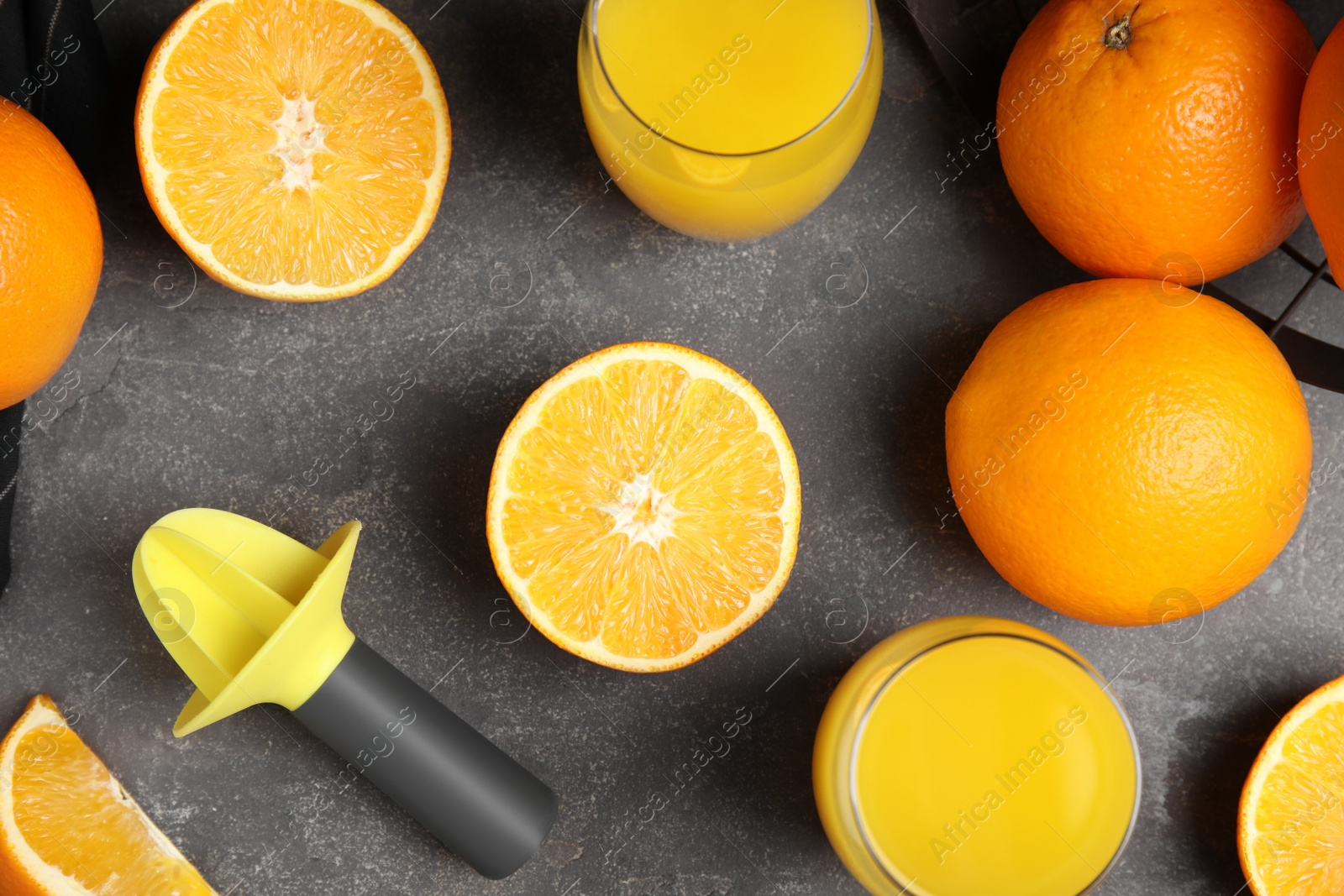 Photo of Fresh ripe oranges, reamer and juice on grey table, flat lay