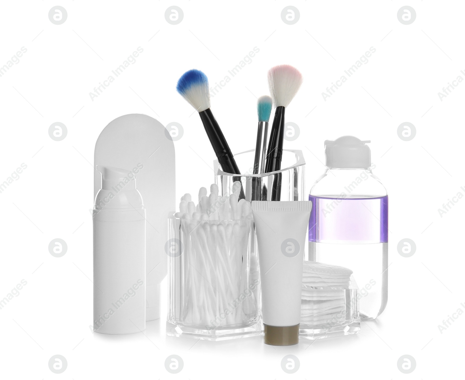 Photo of Cosmetic products near holder with brushes, cotton swabs and pads on white background