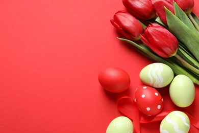 Photo of Flat lay composition of painted Easter eggs and spring flowers on color background, space for text