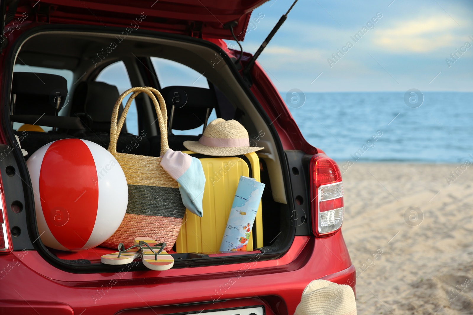 Photo of Red car with luggage on beach, closeup. Summer vacation trip