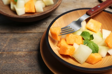 Photo of Salad with assorted melons in plate on wooden background