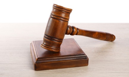 Photo of Wooden gavel on light table against white background