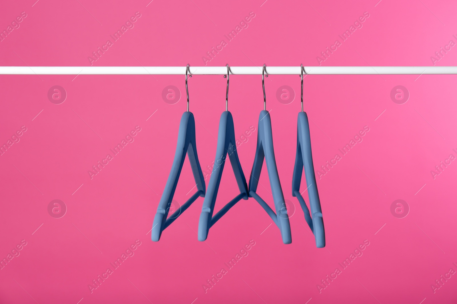 Photo of Metal rack with clothes hangers on color background