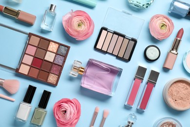 Photo of Flat lay composition with different makeup products and beautiful spring flowers on light blue background