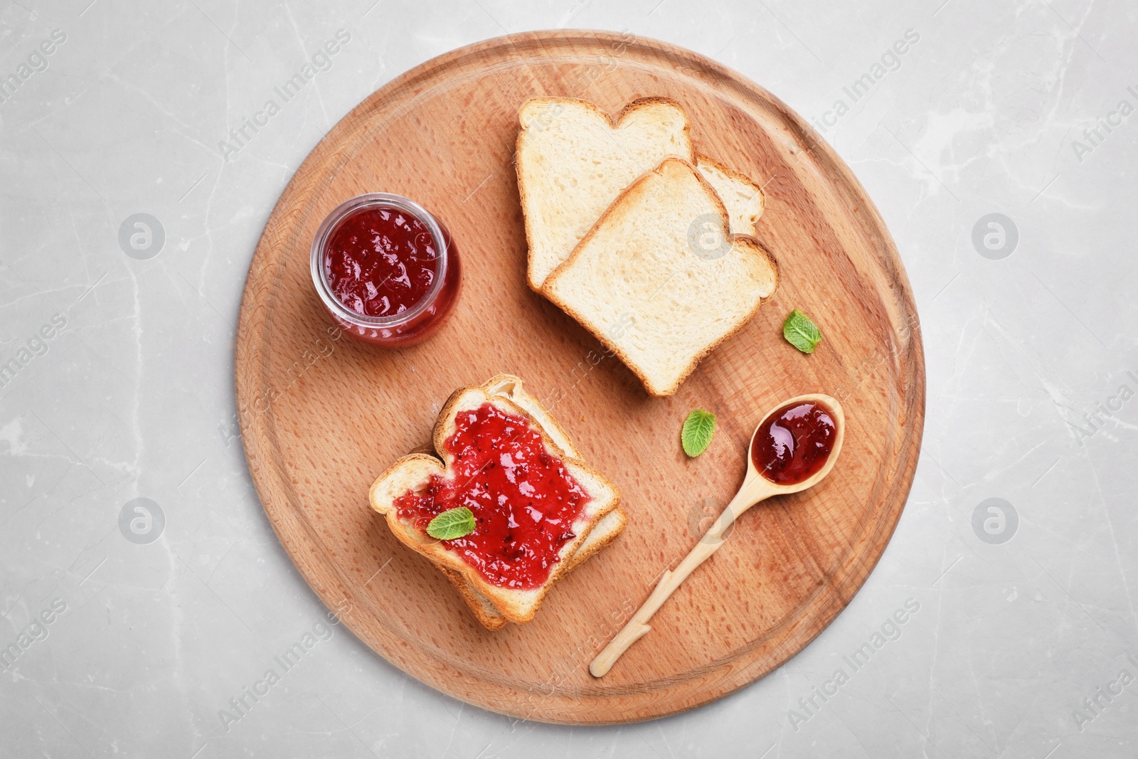 Photo of Toasts with jam on wooden board, top view