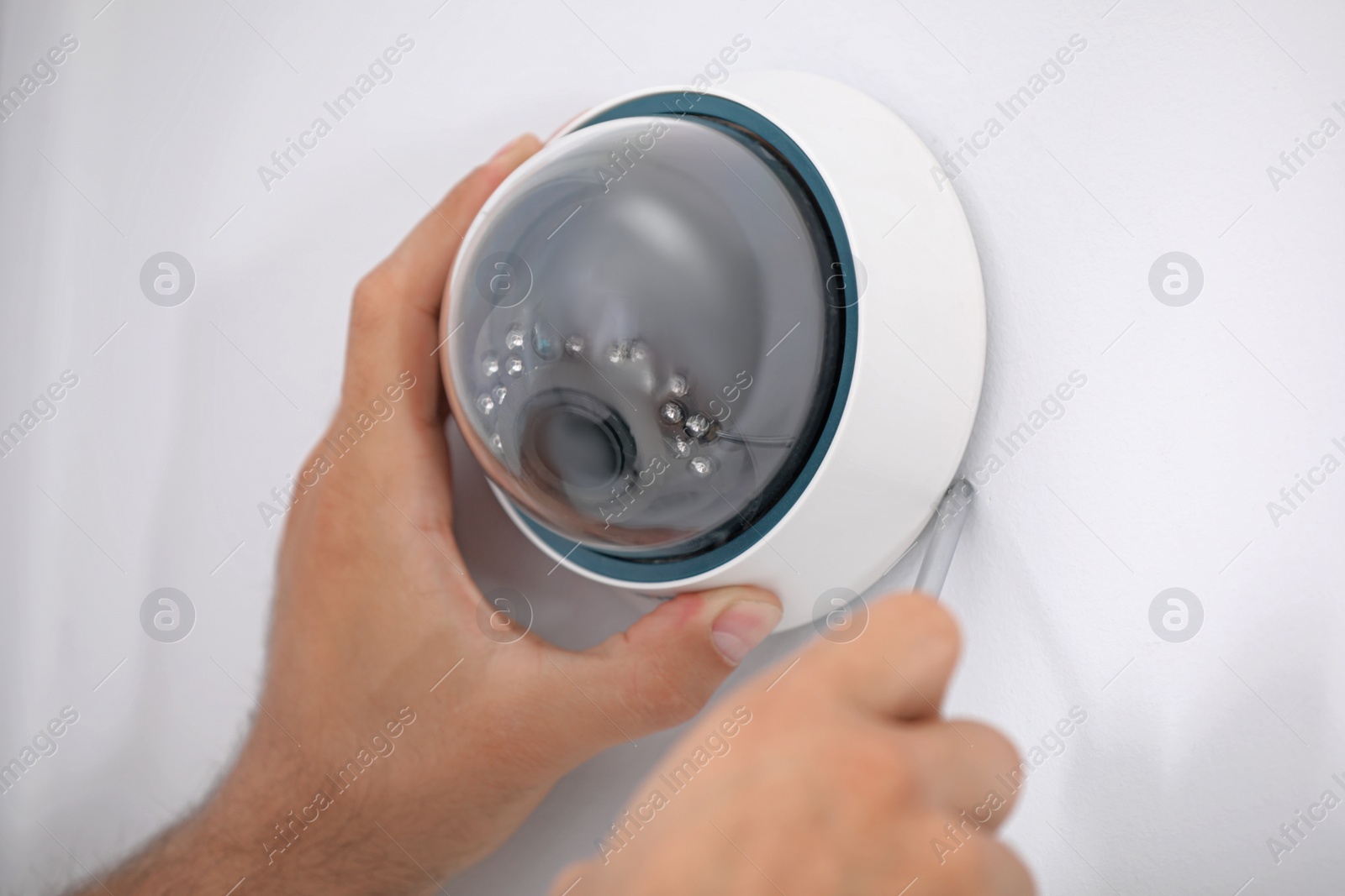 Photo of Technician installing CCTV camera on wall, closeup