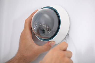 Technician installing CCTV camera on wall, closeup