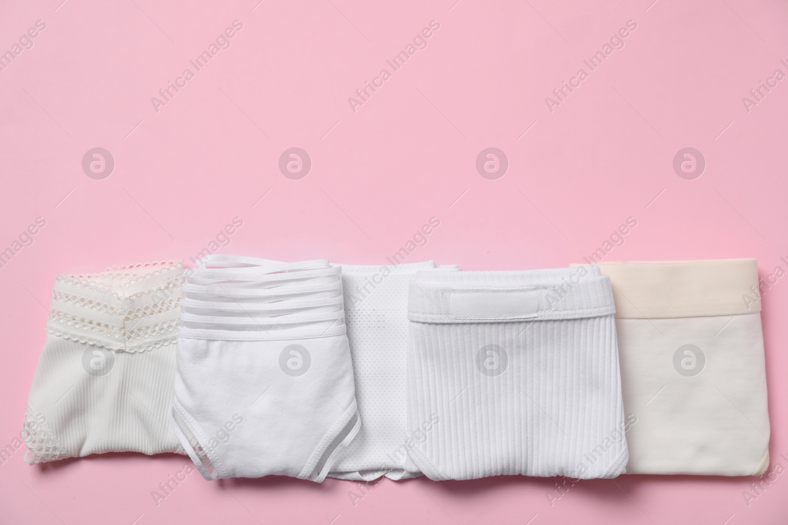 Photo of Stylish folded women's underwear on pink background, flat lay. Space for text