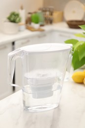 Photo of Water filter jug on white marble table in kitchen