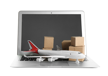 Photo of Laptop, airplane model and carton boxes on white background. Courier service
