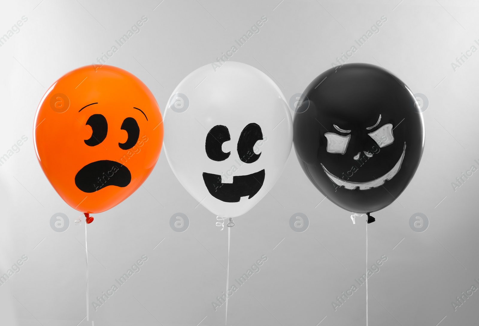 Photo of Spooky balloons for Halloween party on light grey background