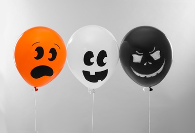 Photo of Spooky balloons for Halloween party on light grey background