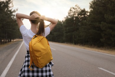 Photo of Woman with backpack on road near forest, back view