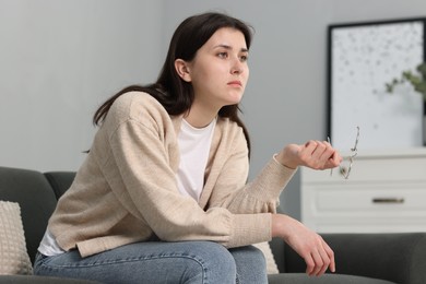 Photo of Overwhelmed woman with glasses sitting on sofa at home