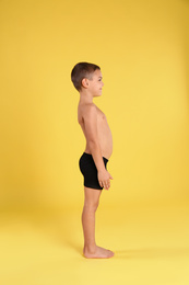 Photo of Cute little boy in underwear on yellow background