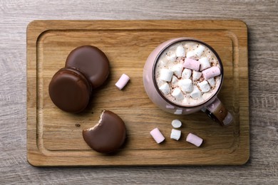 Photo of Tasty choco pies and cocoa with marshmallows on wooden table, top view