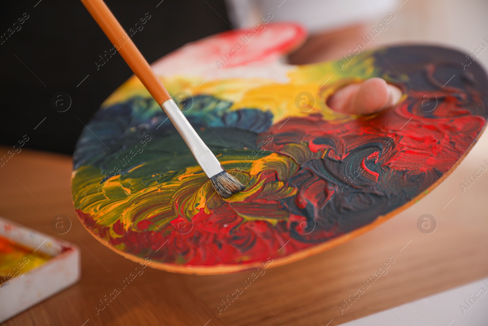 Photo of Young man with palette and brush at table, closeup. Painting artist