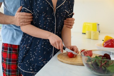 Photo of Couple in pajamas cooking at kitchen counter, closeup