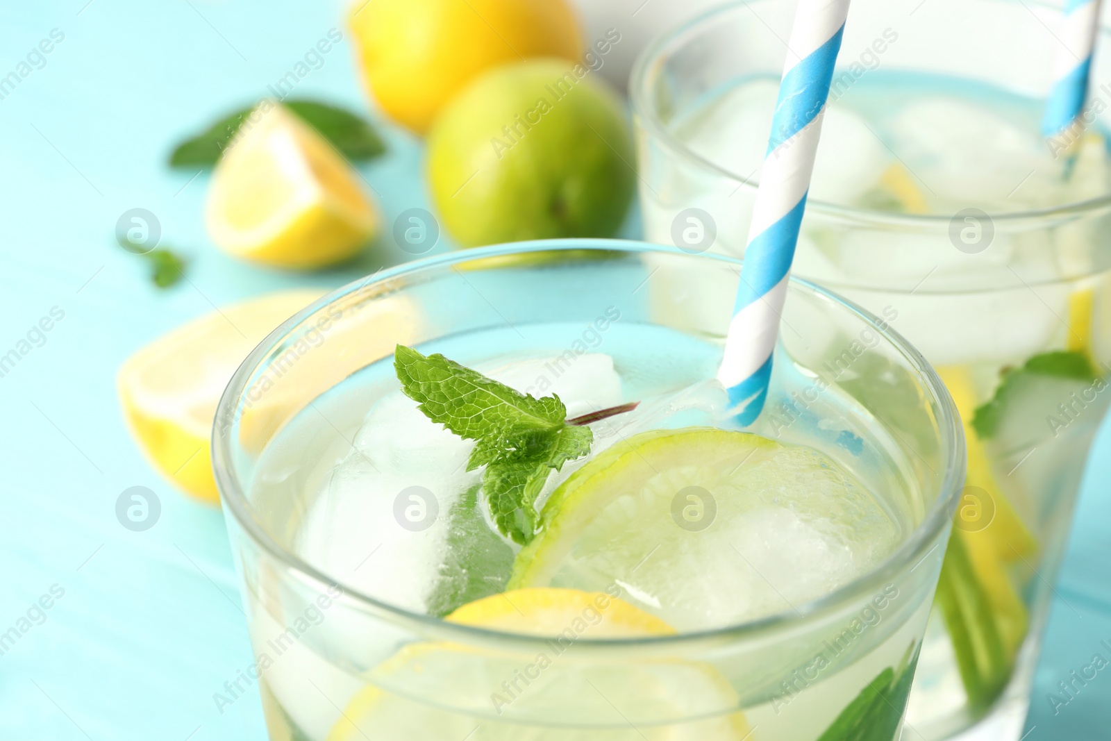 Photo of Glass of refreshing lemonade on light blue table, closeup. Summer drink