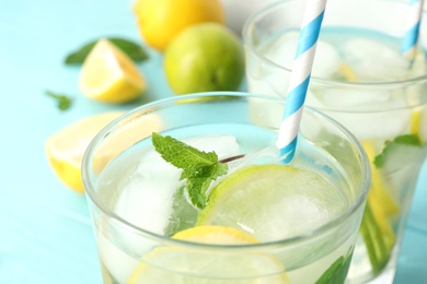 Photo of Glass of refreshing lemonade on light blue table, closeup. Summer drink