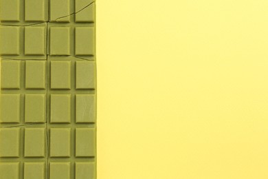 Pieces of tasty matcha chocolate bar on yellow background, top view. Space for text
