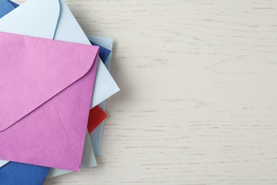 Photo of Colorful paper envelopes on white wooden background, top view. Space for text