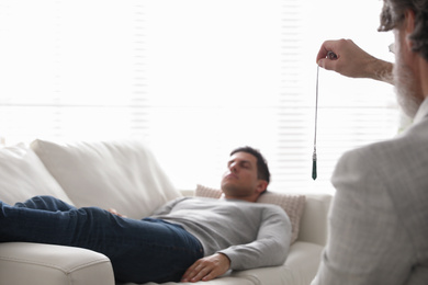 Photo of Psychotherapist using pendulum during hypnotherapy   session in office