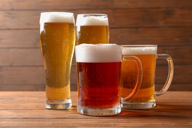 Photo of Glasses with different types of cold tasty beer on wooden table