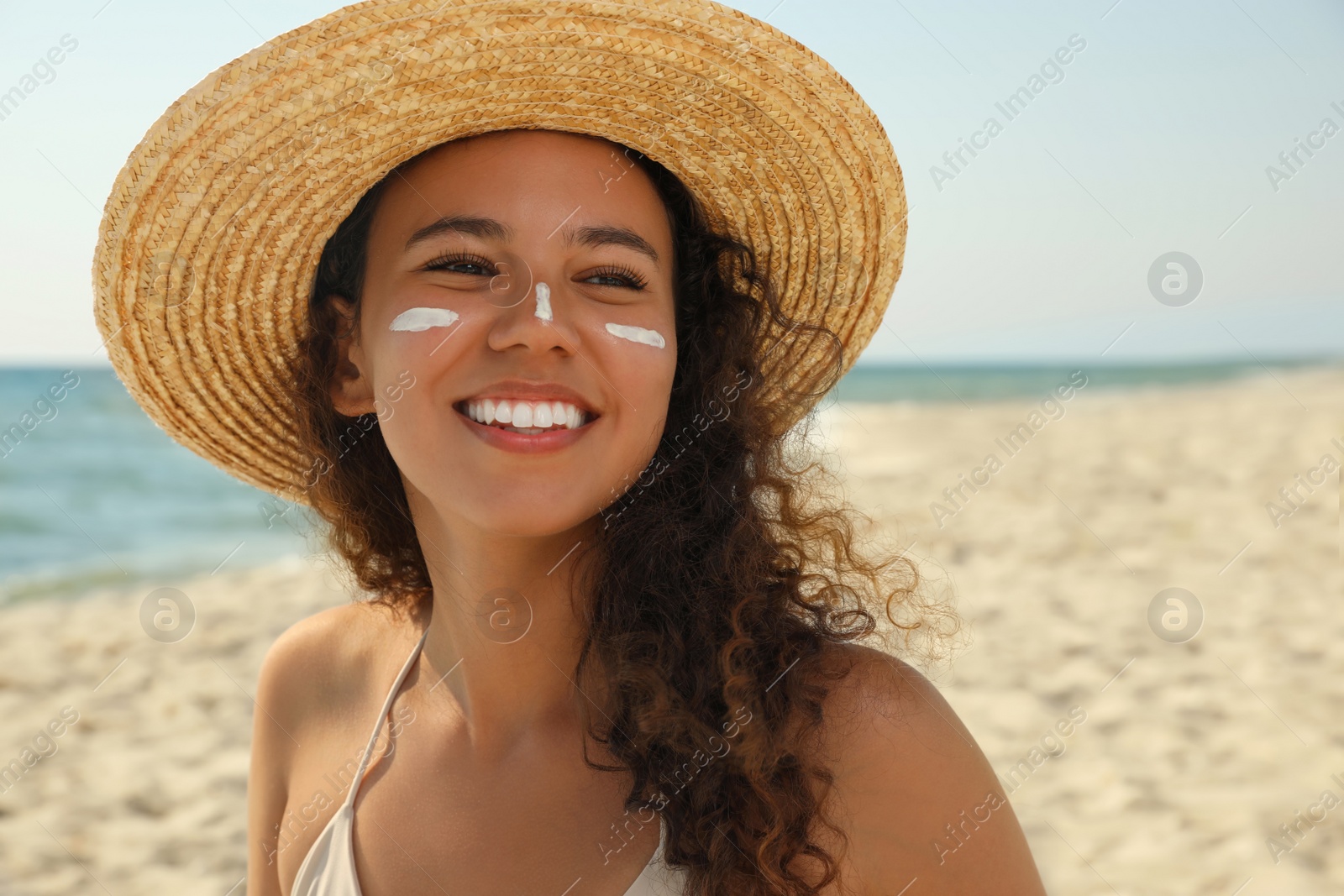 Photo of Beautiful African American woman with sun protection cream on face at beach